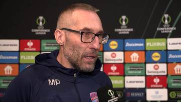 Portret Marka Papszuna, trenera, podczas wywiadu na tle ścianki sponsorskiej z logo Ligi Konferencji Europy.