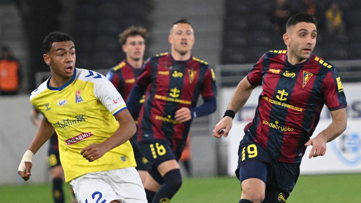 Dwóch piłkarzy w zbliżeniu podczas meczu piłki nożnej. Jeden w żółtej koszulce, drugi w granatowo-czerwonej.