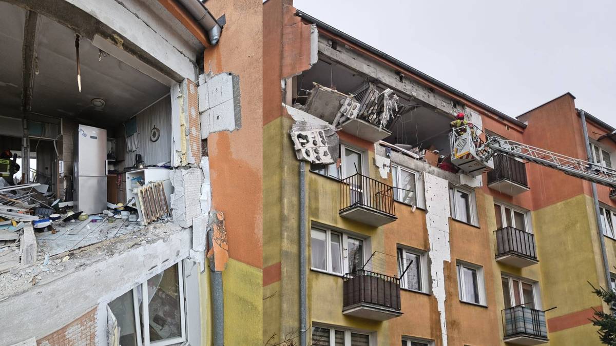 Zniszczony blok mieszkalny po eksplozji, z widocznymi wyrwanymi ścianami i uszkodzonymi oknami.