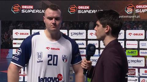 Siatkarz w białej koszulce z numerem 20 i niebieskimi rękawami rozmawia z dziennikarzem podczas wywiadu.