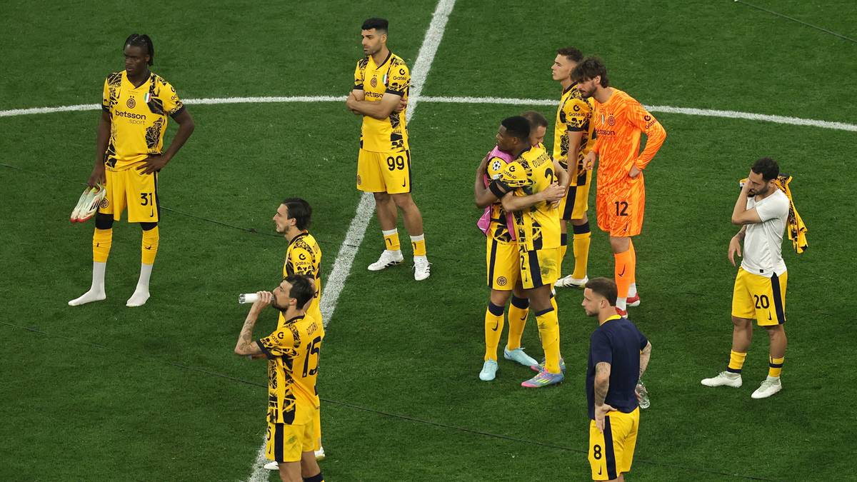 Grupa piłkarzy w żółtych i czarnych strojach stoi na zielonym boisku piłkarskim.