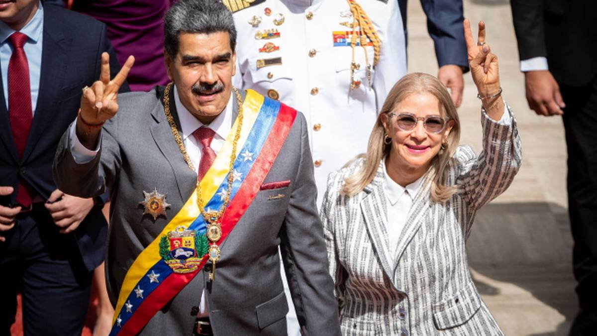 Prezydent Wenezueli Nicolas Maduro i jego żona Cilia Flores pozdrawiają tłum, oboje unoszą dwa palce w geście zwycięstwa.