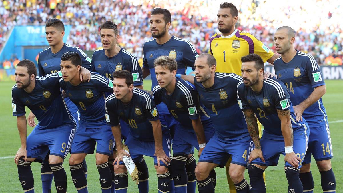 Piłkarze Argentyny w niebieskich strojach stoją w rzędzie na boisku.
