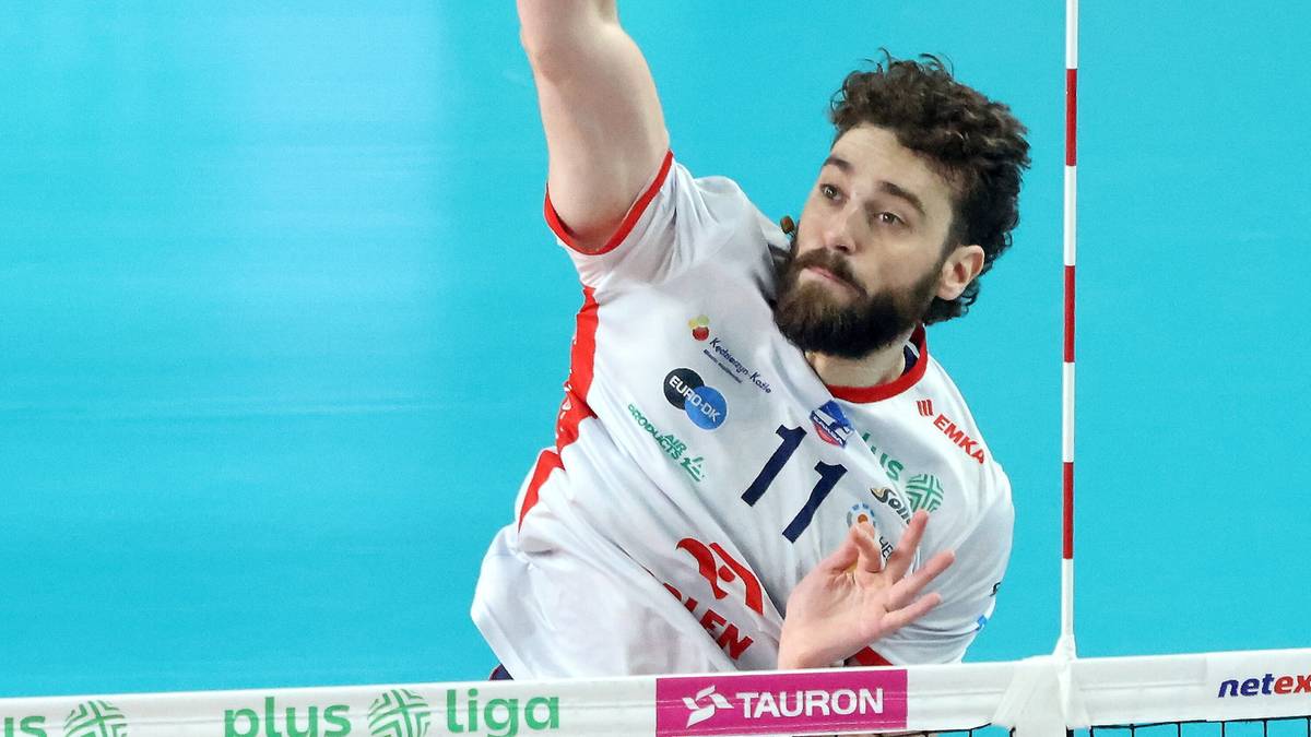 Siatkarz w akcji podczas meczu, wykonuje zagrywkę z wyskoku.