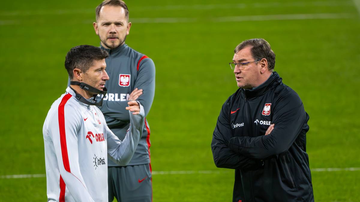 Piłkarze reprezentacji Polski w dresach podczas rozmowy na boisku.