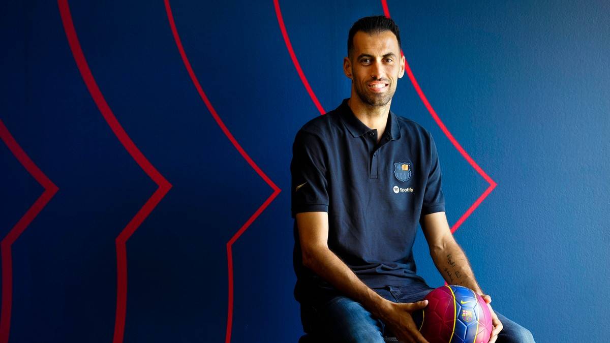 Sergio Busquets siedzi i trzyma piłkę nożną, ubrany w koszulkę FC Barcelona.