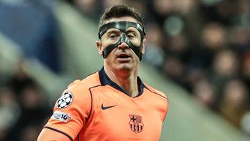 Piłkarz Robert Lewandowski w pomarańczowej koszulce FC Barcelony z numerem 9 na plecach i maską ochronną na twarzy.