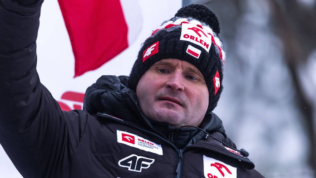 Mężczyzna w czapce z pomponem i kurtce zimowej, trzymający w górze biało-czerwoną flagę.