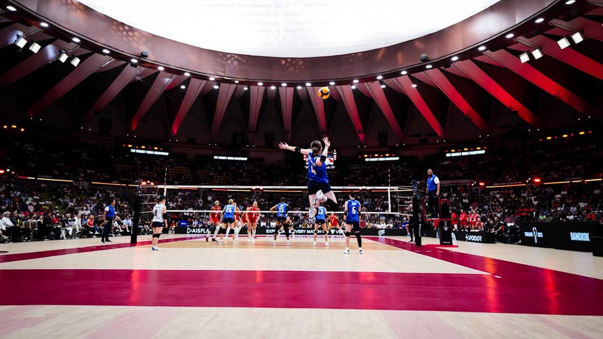 Siatkarka w skoku atakuje piłkę podczas meczu w wypełnionej po brzegi hali.
