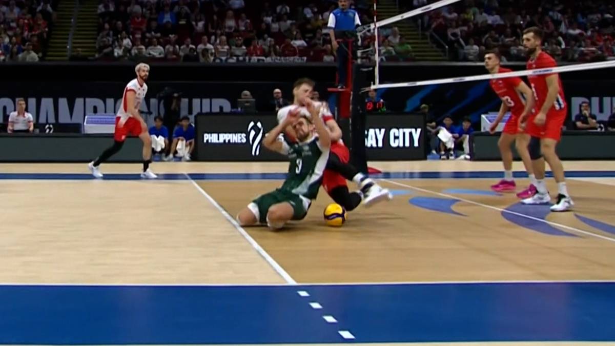 Dwóch polskich siatkarzy zderza się na boisku, jeden z nich leży na ziemi przy piłce.