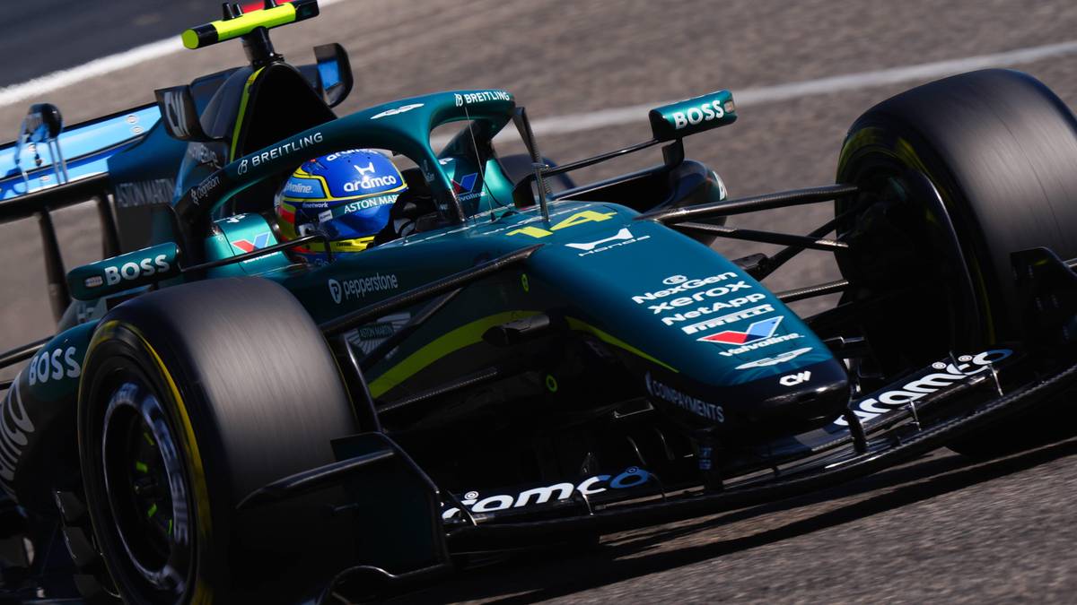 Samoch&oacute;d Formuły 1 zespołu Aston Martin w ruchu na torze wyścigowym, z widocznym kierowcą w kasku.