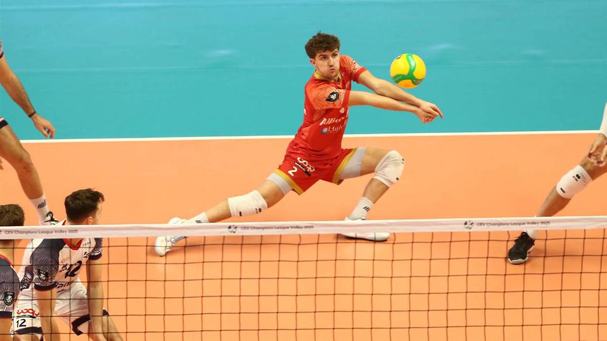 Siatkarz w czerwonym stroju wykonuje przyjęcie zagrywki, z piłką w powietrzu.