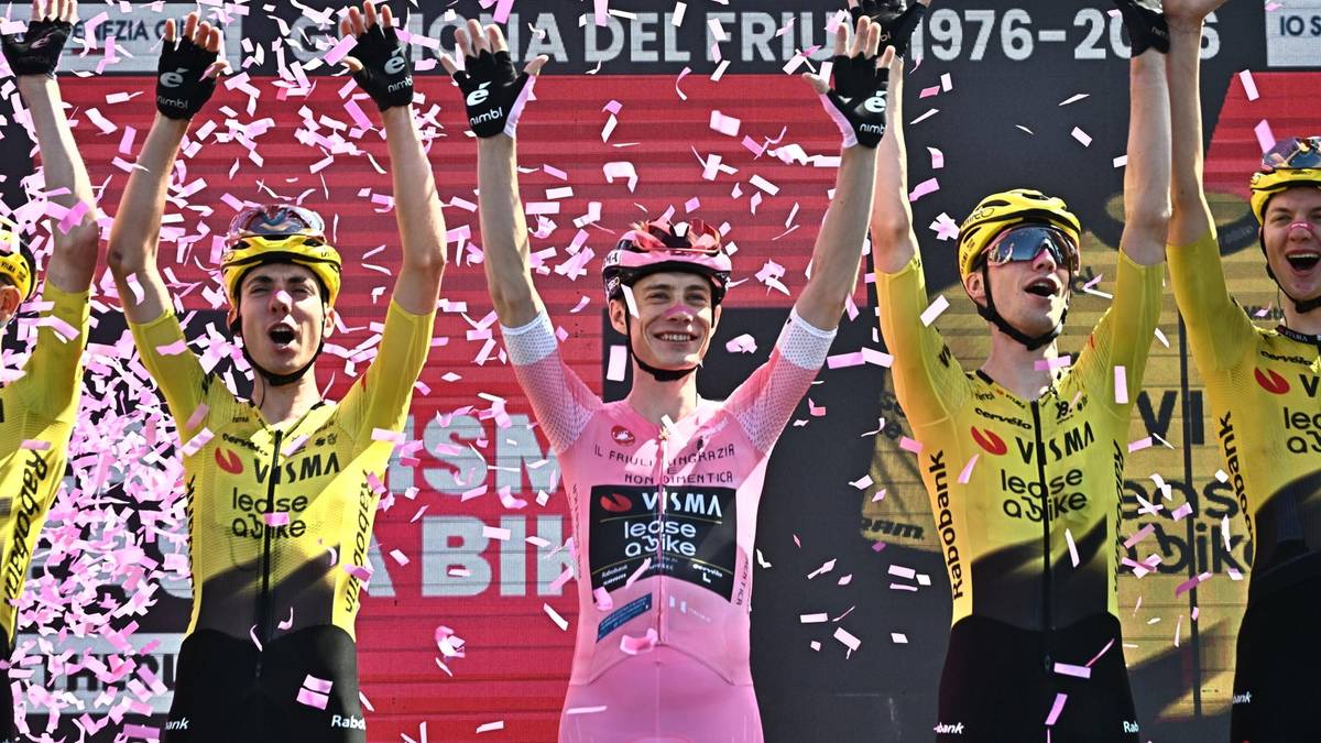 Jonas Vingegaard w r&oacute;żowej koszulce lidera, otoczony przez koleg&oacute;w z drużyny Visma-Lease a Bike, świętuje zwycięstwo na podium Giro d'Italia.