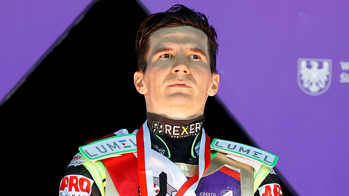 Portret Patryka Dudka, polskiego żużlowca, ubranego w strój sportowy i medal na szyi.