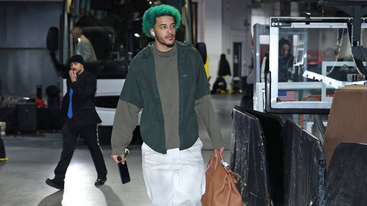 Karl-Anthony Towns idzie z torbą podr&oacute;żną, ubrany w zieloną czapkę i sportowe ciuchy.