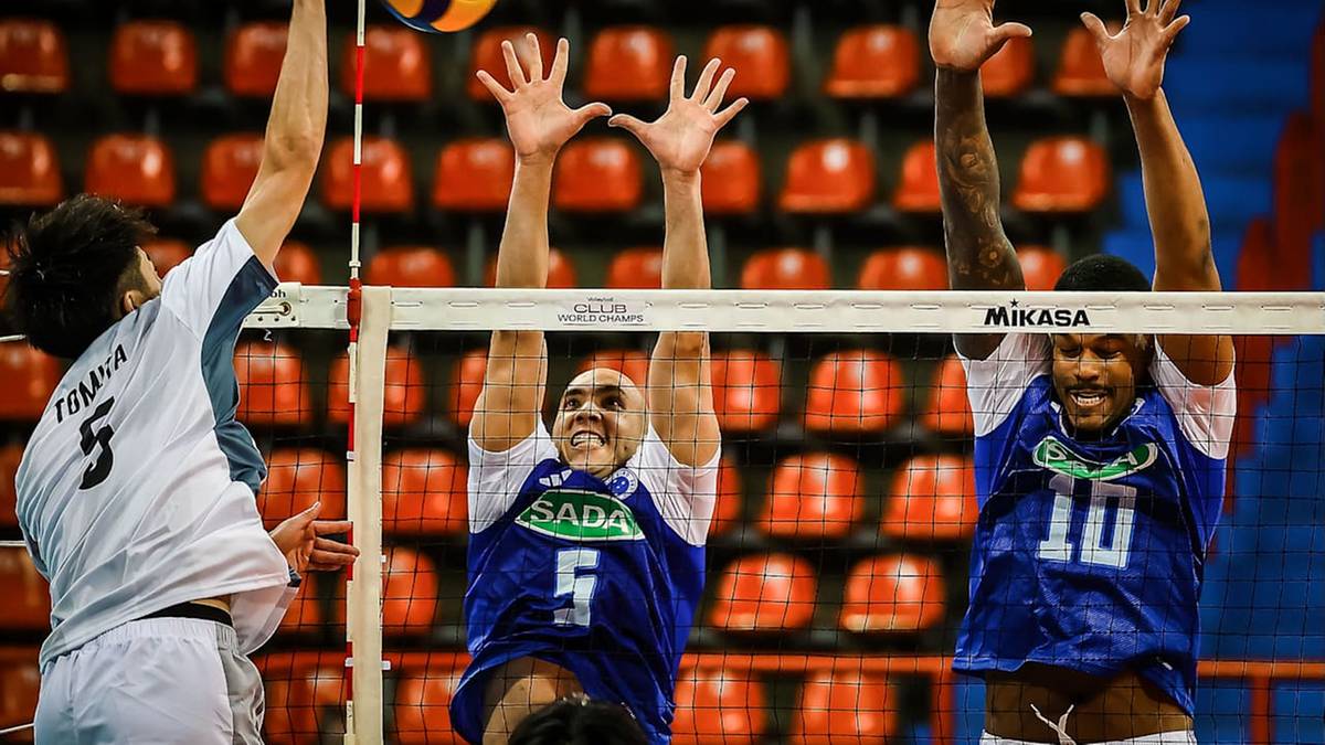 Siatkarze podczas meczu, jeden z nich wykonuje atak nad siatką, dw&oacute;ch pozostałych pr&oacute;buje go zablokować.