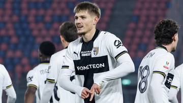 Piłkarz w białej koszulce z numerem 7 na plecach, rozmawiający z kolegą z drużyny na boisku.