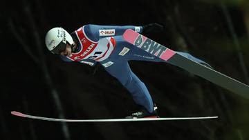 Skoczek narciarski w locie na nartach podczas zawodów.