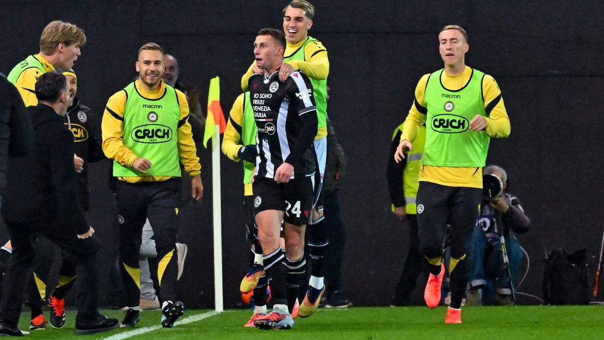 Piłkarz w czarno-białej koszulce, numer 24, cieszy się z zdobytej bramki, otoczony przez kolegów z drużyny w żółtych kamizelkach.