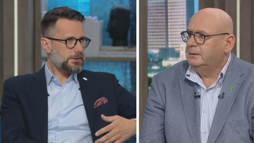 Dw&oacute;ch mężczyzn w garniturach i okularach prowadzi rozmowę w studio telewizyjnym.