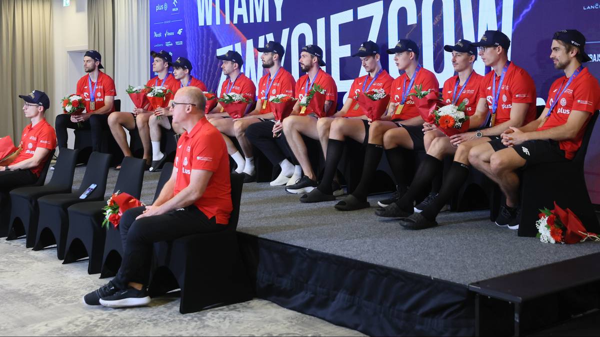 Siatkarze świętujący zwycięstwo na scenie z transparentem powitalnym.