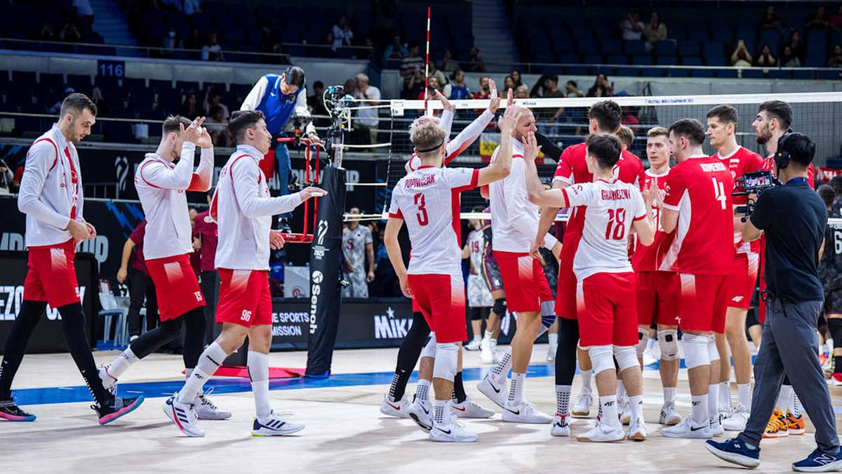 Polscy siatkarze w białych i czerwonych strojach świętują zwycięstwo, stojąc w półokręgu na boisku siatkarskim w hali sportowej.