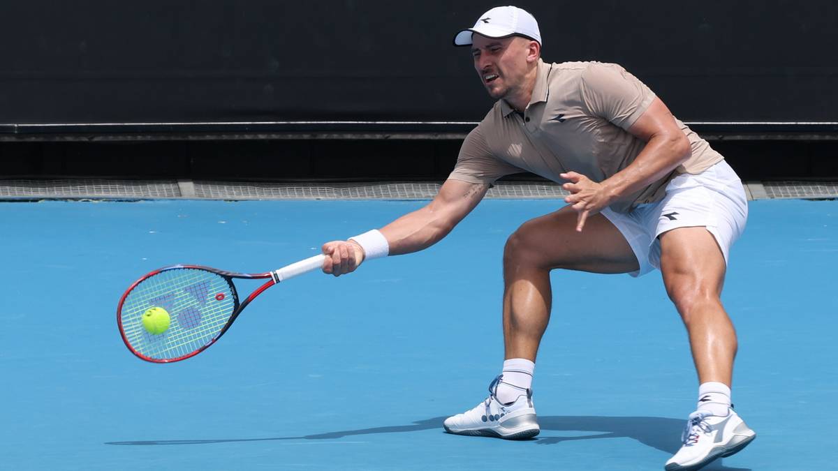 Tenisista w ruchu, wyciąga rakietę do odbicia piłki, która znajduje się w powietrzu przed nim.