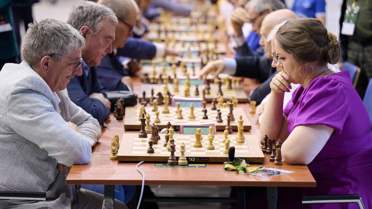 Ludzie grający w szachy na turnieju. Skupieni gracze, szachownice z figurami, atmosfera rywalizacji.