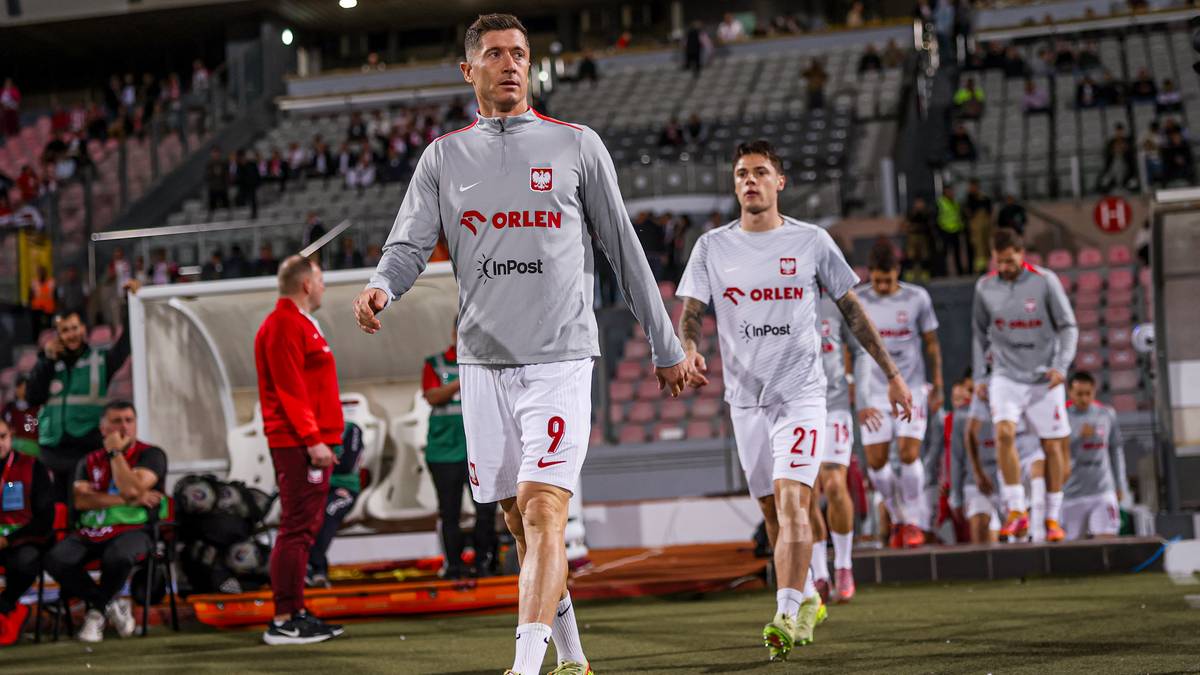 Piłkarze reprezentacji Polski w strojach sportowych, w tym Robert Lewandowski z numerem 9, idący po murawie stadionu.