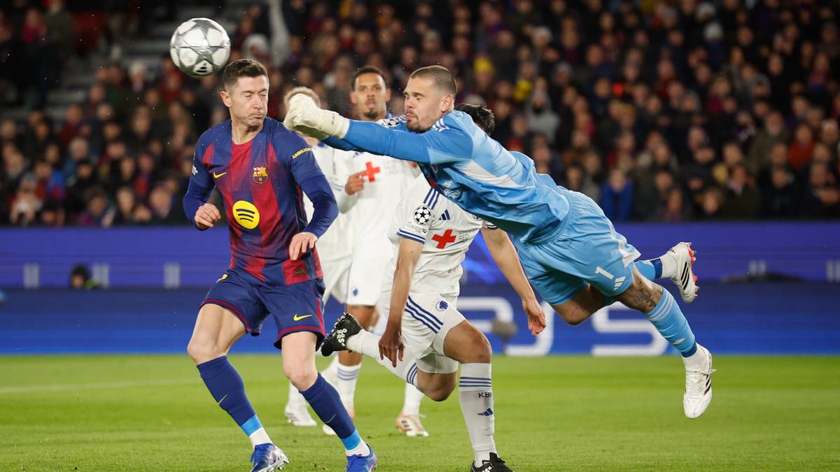 Piłkarz FC Barcelona w niebieskim stroju pr&oacute;buje odebrać piłkę bramkarzowi FC Kopenhaga, kt&oacute;ry interweniuje w powietrzu.