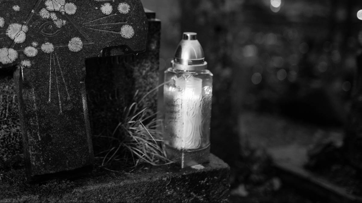 Płonący znicz na grobie.