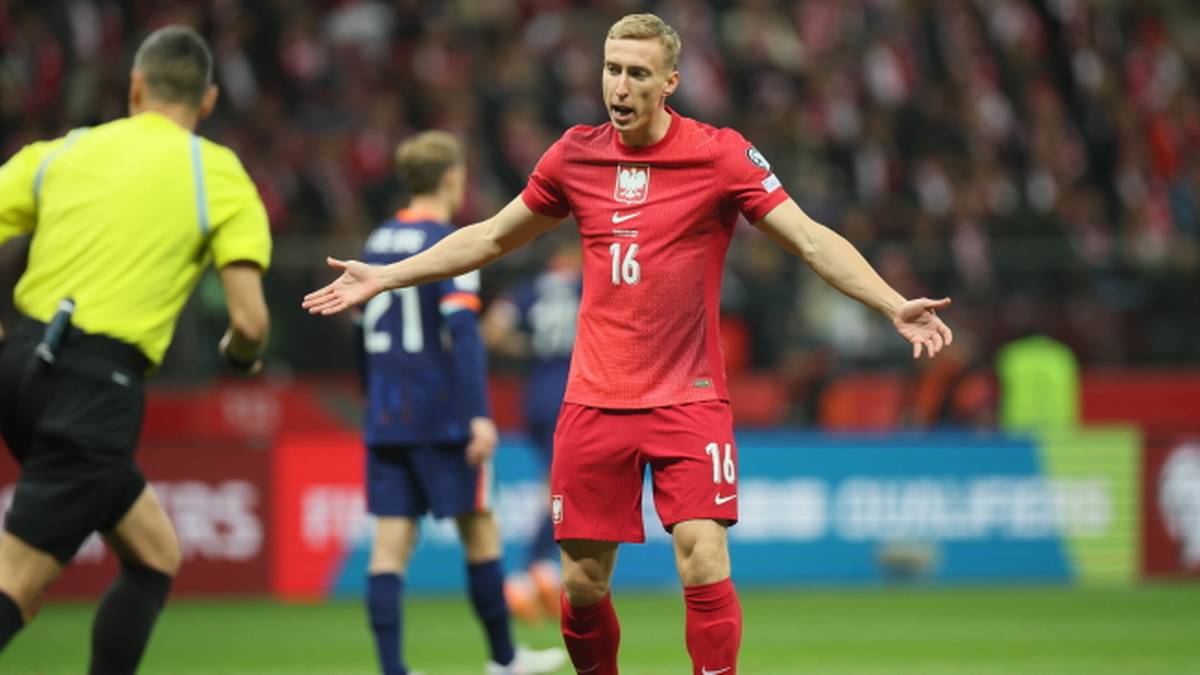 Piłkarz reprezentacji Polski w czerwonej koszulce z numerem 16 na plecach, w geście frustracji lub niedowierzania.
