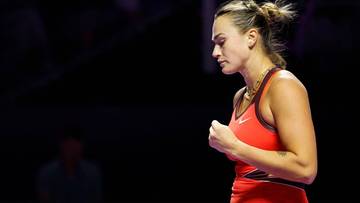 Aryna Sabalenka, tenisistka, zaciśniętą pięścią i zamkniętymi oczami, w czerwonym stroju sportowym.