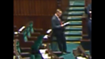 Poseł PO przegląda notatki leżące na miejscu zajmowanym przez prezesa PiS w sali plenarnej