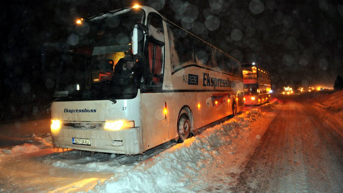 Autokar na ośnieżonej drodze w nocy podczas zamieci.