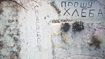 Napis na śniegu "Proszę o chleb" i "Dziękuję", widoczny z perspektywy drona.