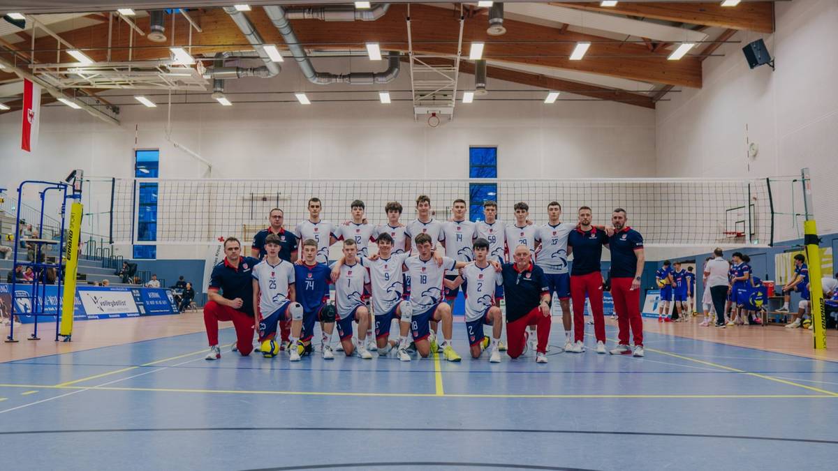 Drużyna siatkarska pozująca do zdjęcia grupowego na boisku sportowym.