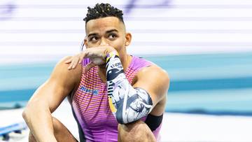 Lekkoatleta Emmanouil Karalis siedzi na ziemi, opierając podbr&oacute;dek na dłoni.