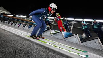 Skoczek narciarski w pozycji startowej na rozbiegu skoczni.