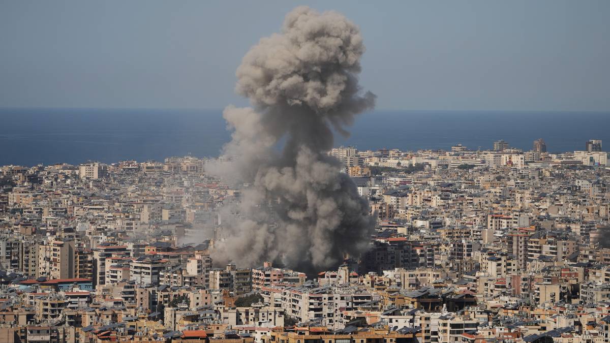 Dym unoszący się nad zabudowanym miastem w pobliżu morza.