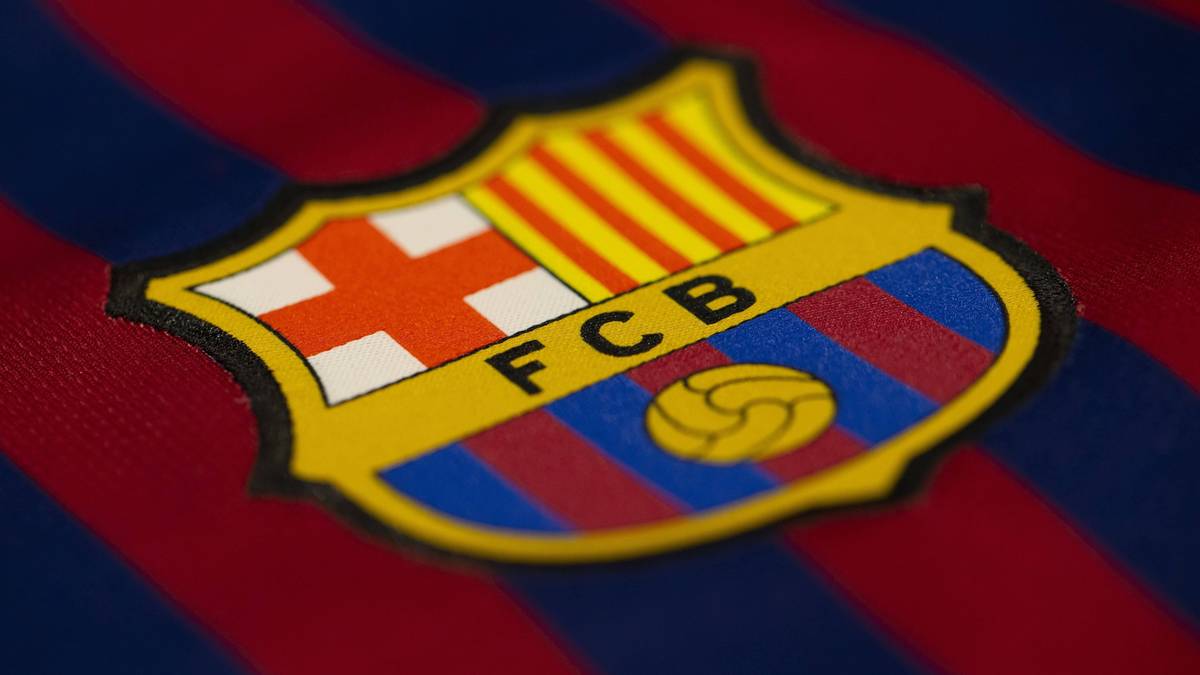 Herb FC Barcelony z widocznym napisem FCB na tle czerwono-granatowej koszulki.