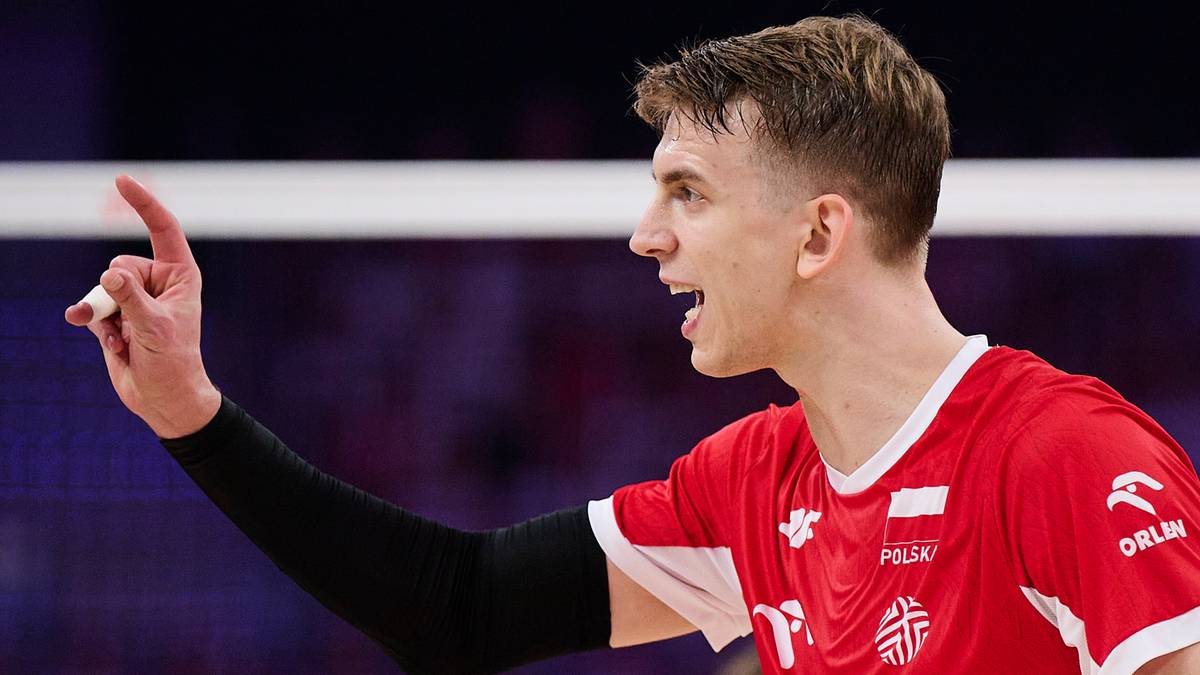 Młody mężczyzna w czerwonej koszulce z białym orłem na piersi i napisem "POLSKA" wskazuje palcem w górę.