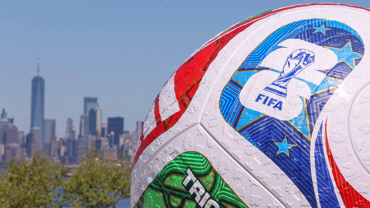 Zbliżenie na piłkę nożną z logo FIFA, w tle miejski krajobraz z wieżowcem