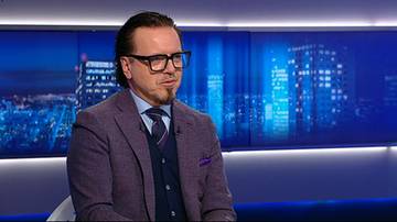 Mężczyzna w marynarce i okularach wypowiadający się w studiu telewizyjnym.
