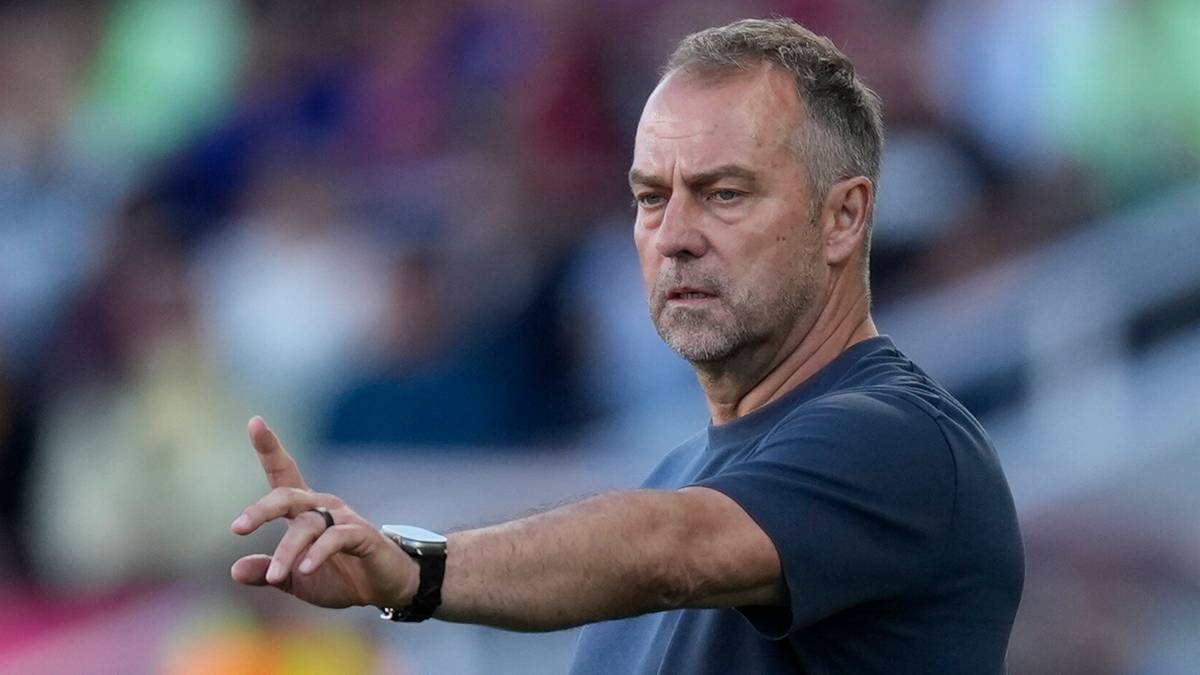 Portret Hansiego Flicka, trenera piłkarskiego, podczas meczu, z ręką uniesioną w geście wskazania.