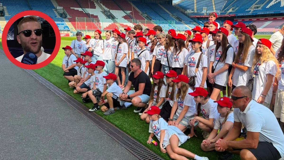 Mężczyzna w okularach przeciwsłonecznych i czerwonym okręgu na tle stadionu.