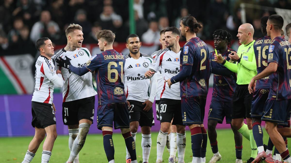 Grupa piłkarzy w strojach Legii Warszawa i Pogoni Szczecin, stojących blisko siebie na boisku po meczu. Niekt&oacute;rzy zawodnicy się uśmiechają i wymieniają gesty.