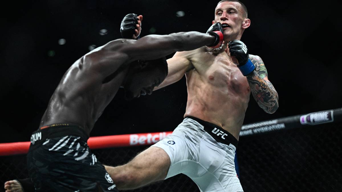 Dwóch zawodników MMA podczas walki w oktagonie, jeden z nich zadaje cios pięścią.