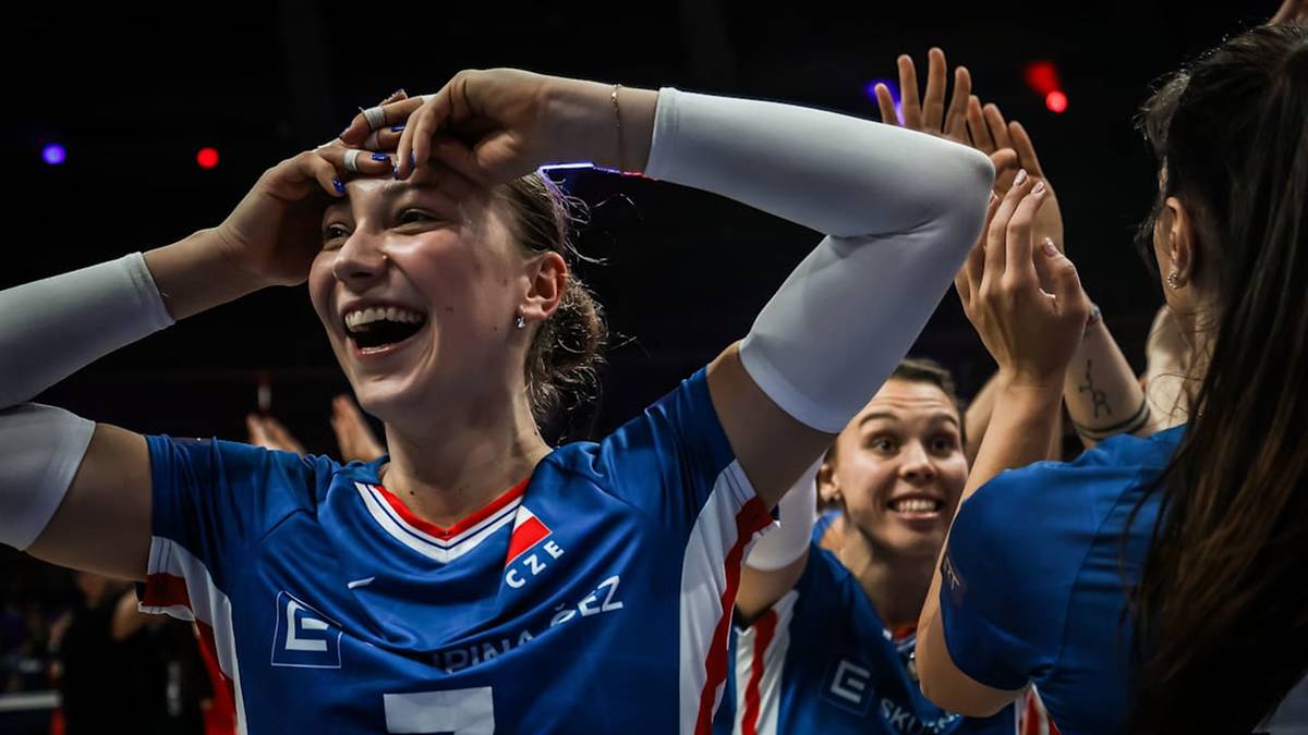 Siatkarka świętuje zwycięstwo z drużyną, dotykając czoła i uśmiechając się szeroko.