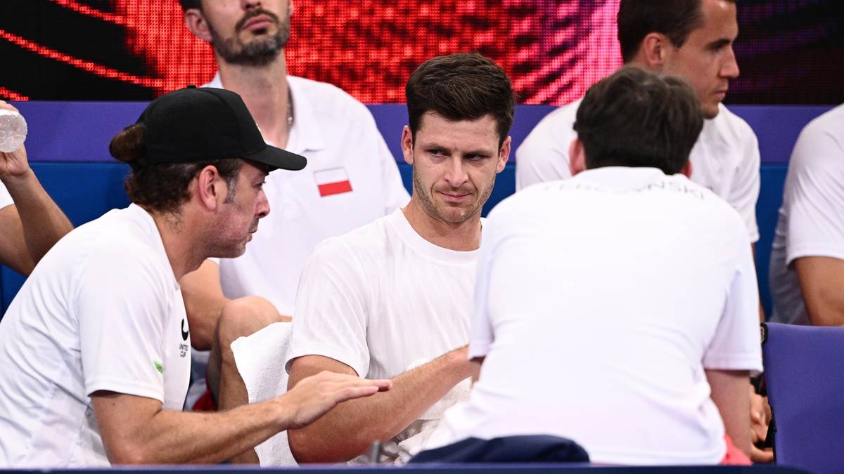 Hubert Hurkacz rozmawia z innymi mężczyznami w białych koszulkach.